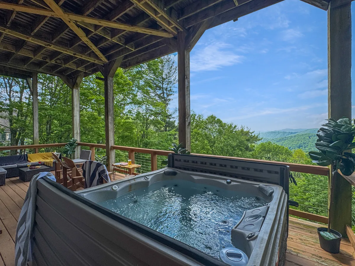 A tranquil exterior featuring a bubbling hot tub with mountain views and a comfortable outdoor seating area. The setting suggests relaxation after a day of winter sports, with the backdrop of natural beauty enhancing the sense of luxury and comfort.